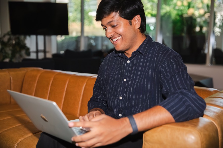 Siddhant from Quality Assurance working from a laptop on the office couch